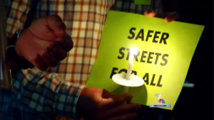 BikeSD vigil participant holds "Safer Streets For All" sign