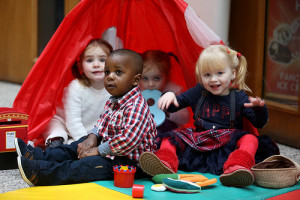 Group of four small children sitting in a group on the floor