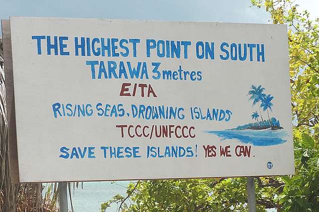 Hand painted sign calling attention to threat of rising sea level to South Tarawa and plea to "Save these islands!"