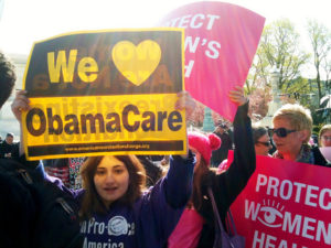 Woman holding sign: "We [heart] Obamacare"